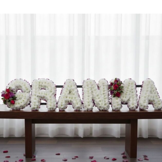 A serene and elegant arrangement of white lilies and roses as grandma funeral flowers for a memorial service.