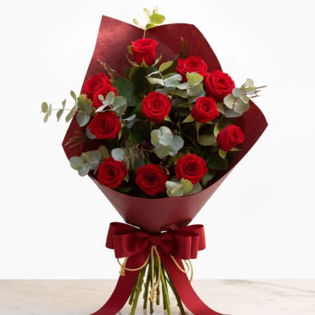 A luxury red rose bouquet with eucalyptus leaves wrapped in premium brown craft paper for a wedding.